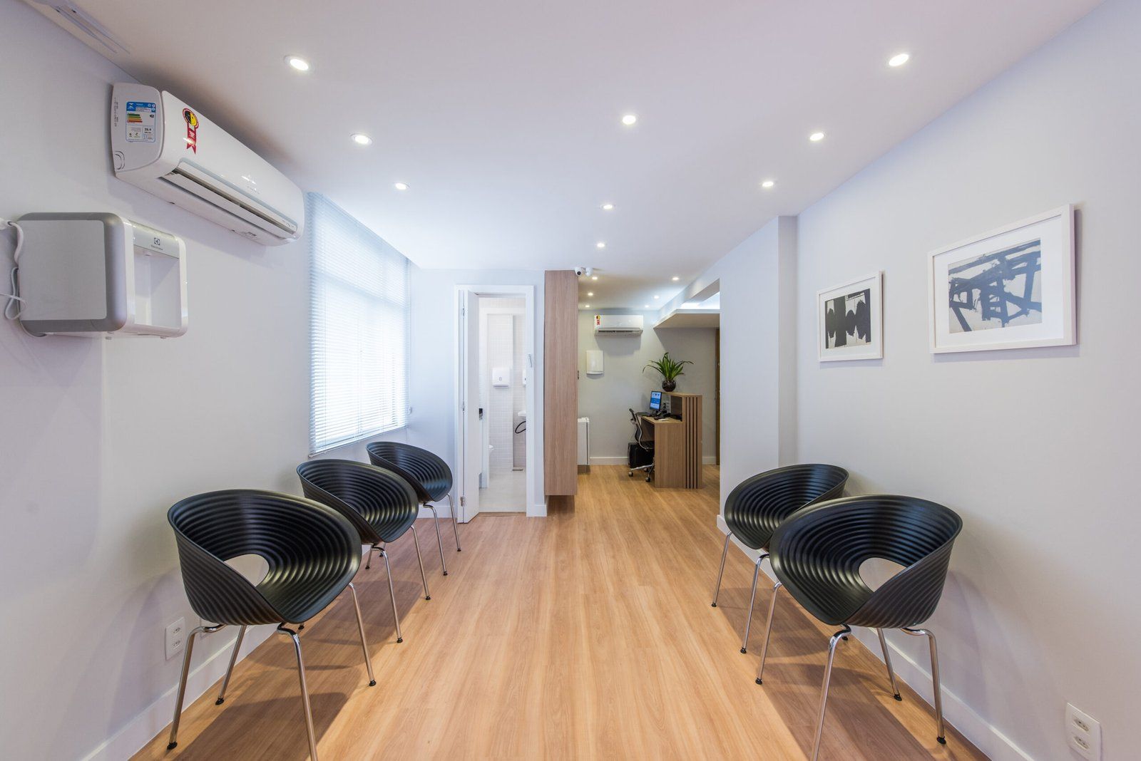Sala de espera da Clínica QARA, com cadeiras e piso de madeira